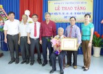 Đồng chí Huỳnh Quang Tiên, Ủy viên Ban Thường vụ Tỉnh ủy, Bí thư Thị ủy Đồng Xoài trao huy hiệu 70 năm tuổi Đảng cho đảng viên Vũ Văn Tiu